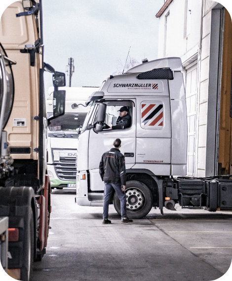 Fahrer im Schwarzmüller-LKW spricht mit Werkstattmitarbeiter – Umsetzung förderfähiger Maßnahmen vor Ort